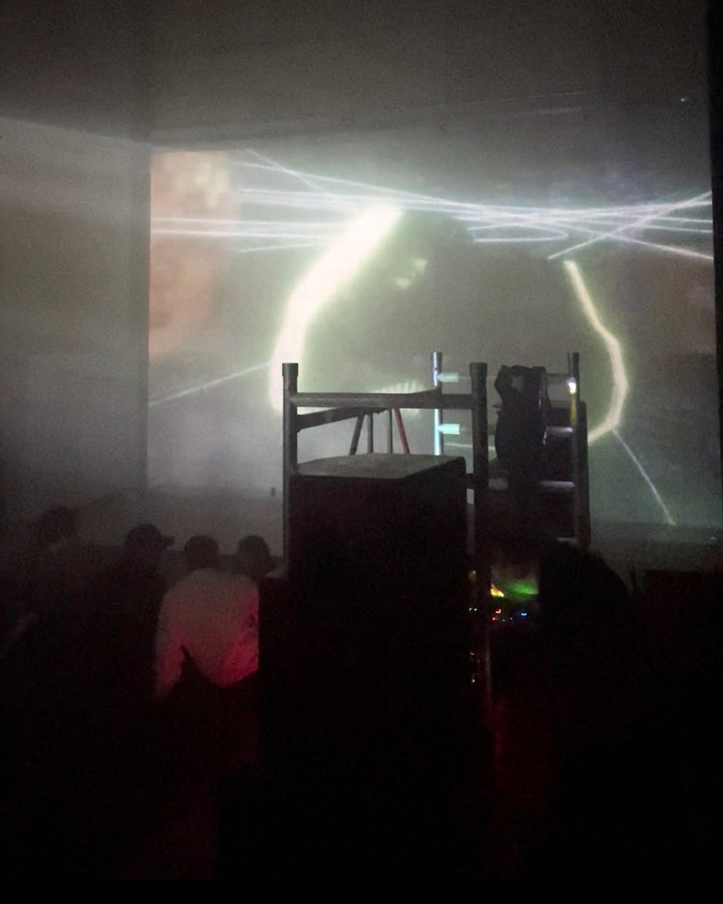 rrrrip9, a night in haze, light traces projected across the room, the crowd in silhouette